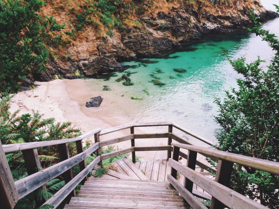 Cala Sonreiras con arena dorada y acantilados verdes